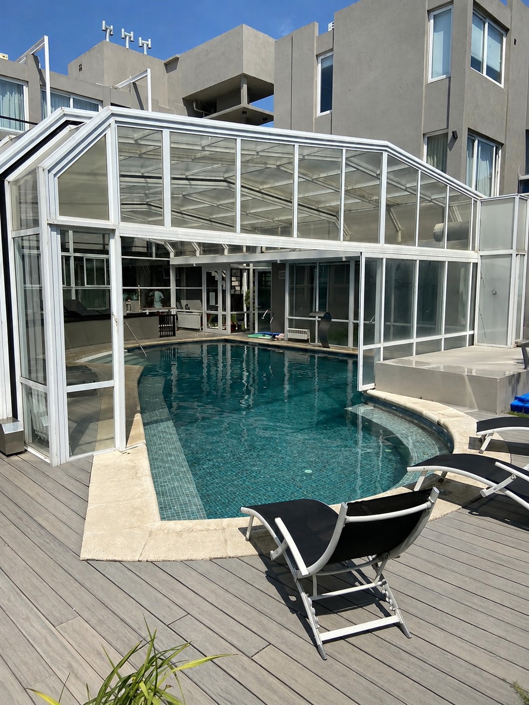 Piscina de AguaBay vista desde el solárium, con cubierta vidriada y reposeras